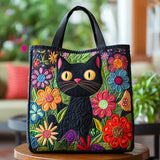 Bolso tote acolchado negro con gato negro entre flores multicolores