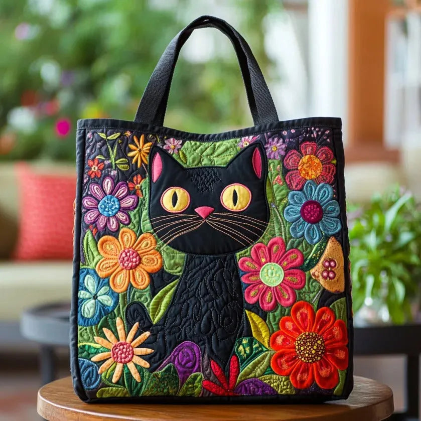 Bolso tote acolchado negro con gato negro entre flores multicolores